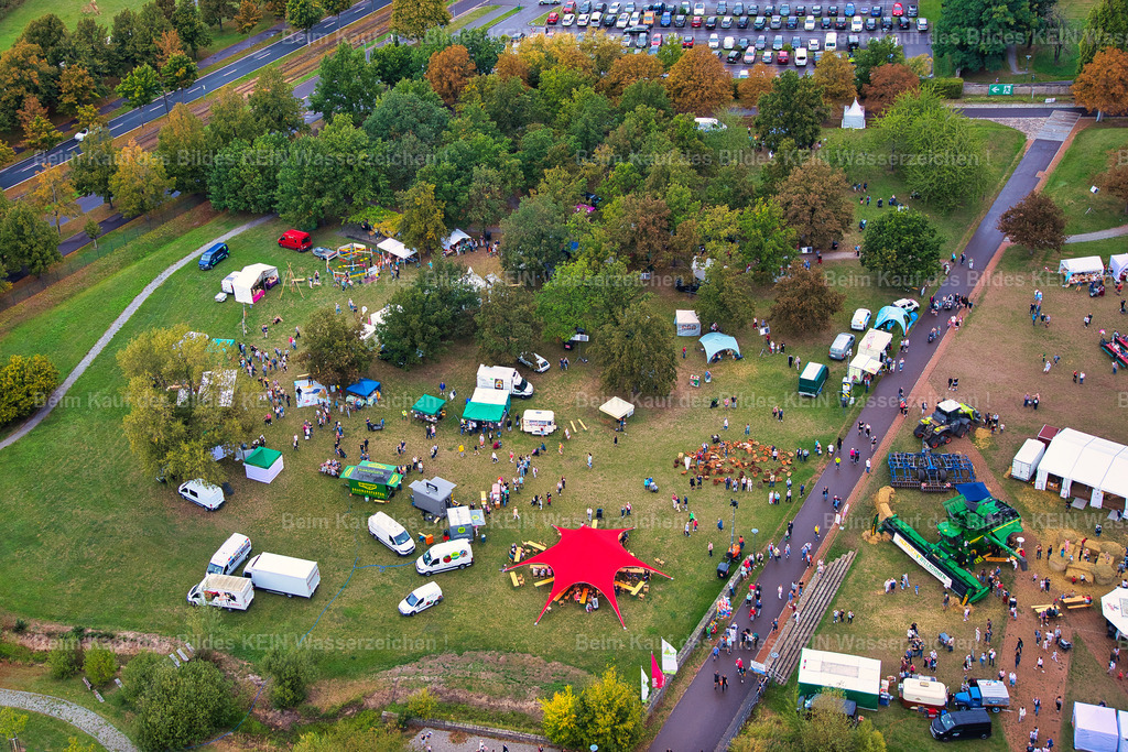 erntedankfest_magdeburg_9616 | Diese Luftaufnahme aus geringer Höhe zeigt das Erntedankfest im Elbauenpark aus einer beeindruckenden Perspektive. Rund um die Seebühne sind die zahlreichen Ausstellerstände, Aktionsflächen und Besucherbereiche hervorragend zu erkennen. Die niedrige Flughöhe des Tragschraubers vermittelt einen lebendigen Eindruck von der Größe und Vielfalt der Veranstaltung und macht die durchdachte Anordnung der einzelnen Bereiche besonders deutlich.Die Aufnahme entstand im Auftrag der Agrarmarketinggesellschaft Sachsen-Anhalt zur Dokumentation des Erntedankfestes. Luftbilder bieten Veranstaltern einen einzigartigen Überblick über das Gelände und zeigen eindrucksvoll, wie sich Aussteller, Präsentationsflächen und Besucherströme harmonisch in den Elbauenpark einfügen. Aus dieser Perspektive wird sichtbar, wie sorgfältig das Fest organisiert ist und welch attraktive Kulisse die Seebühne für eine solche Großveranstaltung bietet.Das Erntedankfest gehört zu den traditionsreichsten Veranstaltungen im Elbauenpark und verbindet regionale Landwirtschaft, kulinarische Spezialitäten, Handwerk und Unterhaltung für die ganze Familie. Diese Luftaufnahme hält nicht nur die besondere Atmosphäre des Festes fest, sondern dokumentiert zugleich einen wichtigen Treffpunkt für Besucher aus ganz Sachsen-Anhalt. - Realisiert mit Pictrs.com