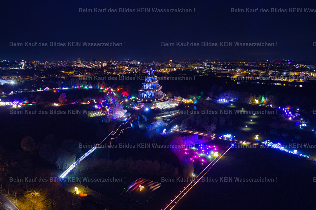 lumagica_Magdeburg_Jahrtausendturm_Nachts_1_0012 | Diese stimmungsvolle Luftaufnahme zeigt den Jahrtausendturm während der Lichtausstellung **Lumagica** im Elbauenpark. Farbenfrohe Lichtinstallationen und kunstvoll illuminierte Wege verwandeln den Park in eine faszinierende Erlebniswelt. Der angestrahlte Jahrtausendturm bildet den Mittelpunkt der Szenerie und setzt sich eindrucksvoll von der nächtlichen Umgebung ab. Erst aus der Luft wird sichtbar, wie harmonisch sich die Lichtkunst in die Parklandschaft einfügt.Mit **Lumagica** hat sich der Elbauenpark in den Wintermonaten zu einem beliebten Ausflugsziel entwickelt. Tausende Besucher erleben jedes Jahr die aufwendig gestalteten Lichtinstallationen, die den Park in eine märchenhafte Kulisse verwandeln. Der Jahrtausendturm bildet dabei das weithin sichtbare Wahrzeichen und sorgt gemeinsam mit den farbenfrohen Illuminationen für eine ganz besondere Atmosphäre.Diese Luftaufnahme verbindet moderne Lichtkunst mit einem der bekanntesten Wahrzeichen Magdeburgs. Sie zeigt den Elbauenpark einmal von einer völlig anderen Seite und macht deutlich, warum die Kombination aus Architektur, Natur und Lichtinszenierung Jahr für Jahr zahlreiche Besucher begeistert. - Realisiert mit Pictrs.com