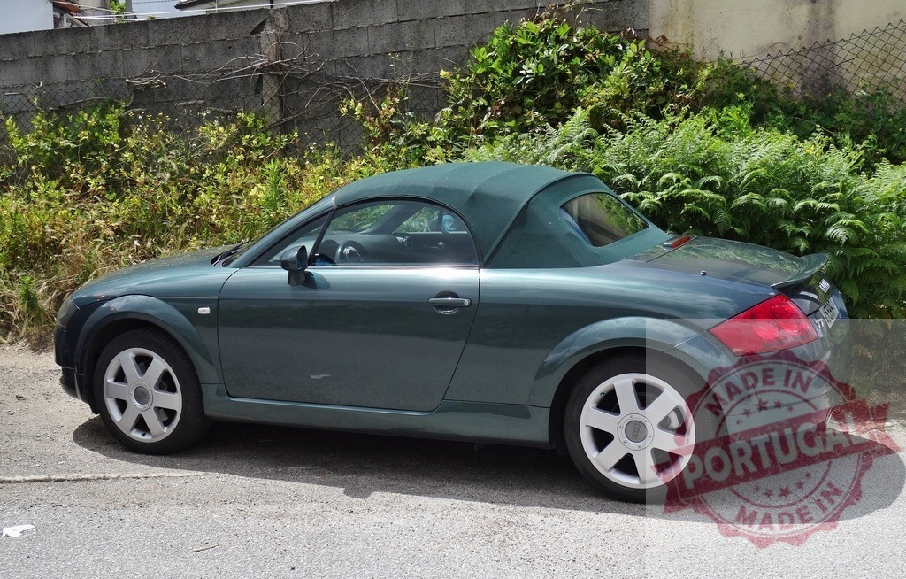 Audi TT first generation dark green convertible car | Audi TT convertible car parked on a road next to a wall with green plants - Realisiert mit Pictrs.com