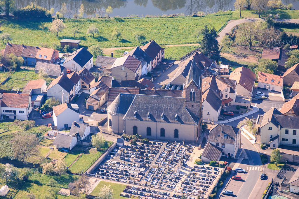 Vue aérienne: Église et cimetière sur les rives de la Sarre à Sarreinsming dans le département Moselle, France – .Photo: IMG_154997.jpg prise le 18/04/2026 par Werner Riehm/FLY-FOTO.eu – Résolution de l'original: 5286 x 3524 px