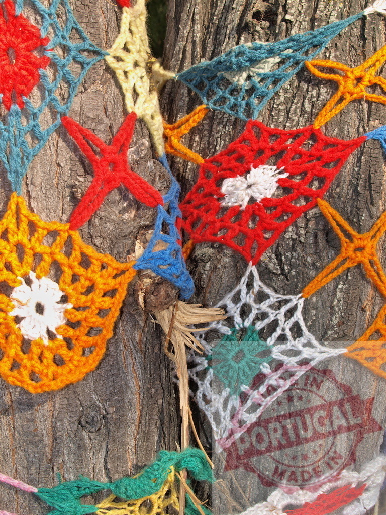 Colorful crochet yarn bombing wrapping tree trunk | Bright knitted textile art creating a decorative cozy on tree bark - Realisiert mit Pictrs.com