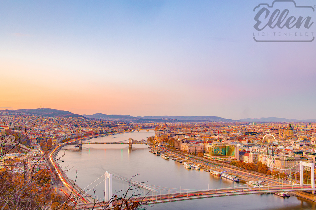 Evening Embrace | From above, Budapest unfolds in gentle hues of gold and violet. As the evening settles, the bridges shimmer across the Danube — connecting not just Buda and Pest, but light, motion, and calm. - Realisiert mit Pictrs.com