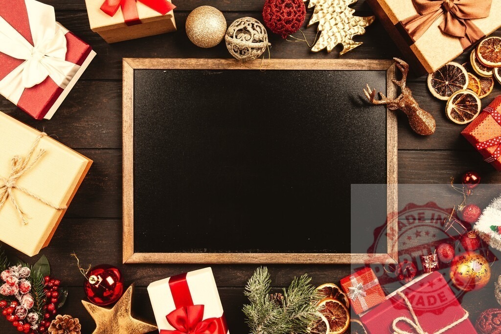 Christmas decorations surrounding a blank blackboard on a wooden table | Christmas decorations and gift boxes forming a frame around a blank blackboard on a wooden table, creating a festive holiday scene - Realized with Pictrs.com