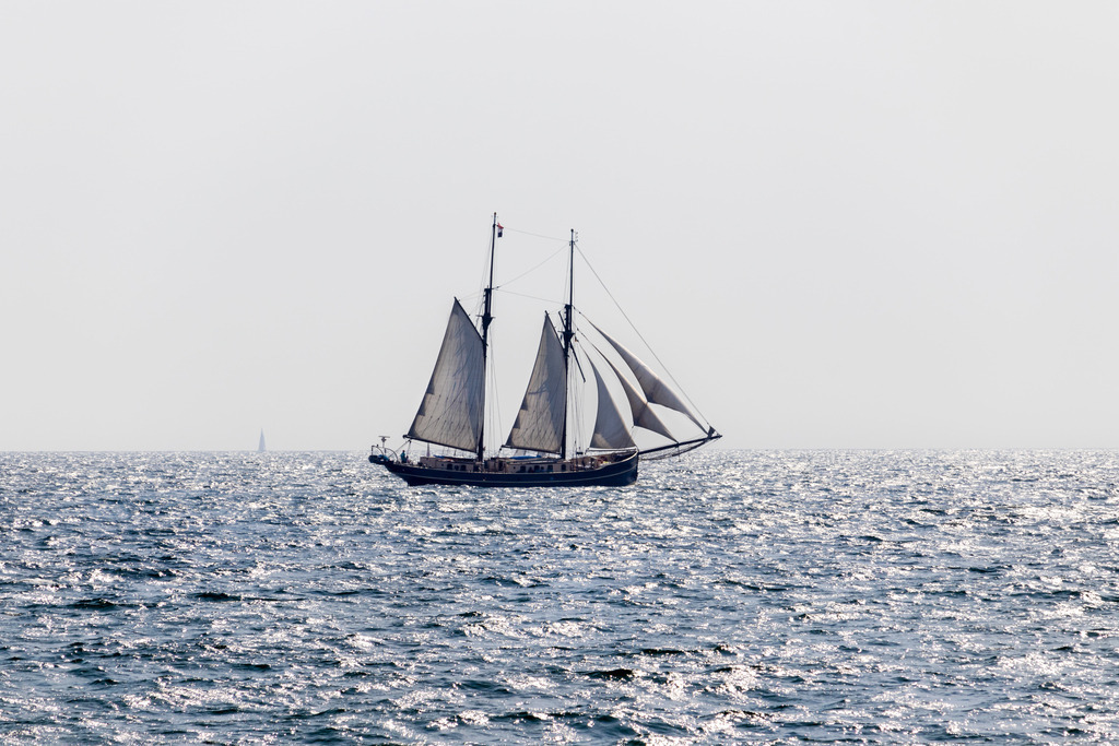 Wandbild: Traditionssegler vor Schönhagen | Dieses Wandbild im Querformat zeigt einen Traditionssegler vor Schönhagen. Durch die tiefstehende Sonne ergeben sich schöne Lichtreflexionen auf dem Meer.  - Realisiert mit Pictrs.com