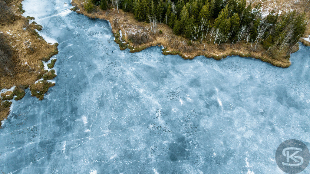 Zugefrorener See im Allgäu – Drohnenaufnahme von Eisstrukturen am Ufer | Beeindruckende Luftaufnahme eines vollständig zugefrorenen Sees im Allgäu. Die Drohnenfotografie zeigt faszinierende Eisstrukturen, Uferbereiche und natürliche Wintermuster aus der Vogelperspektive – einzigartige Winterlandschaft von oben. - Realisiert mit Pictrs.com