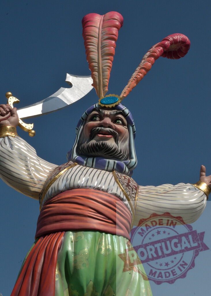 Arabian pirate sultan carnival float against blue sky. Fallas Fiestas Communidad Valenciana | Colorful carnival float depicting a Sultan or genie character holding a scimitar sword - Realized with Pictrs.com