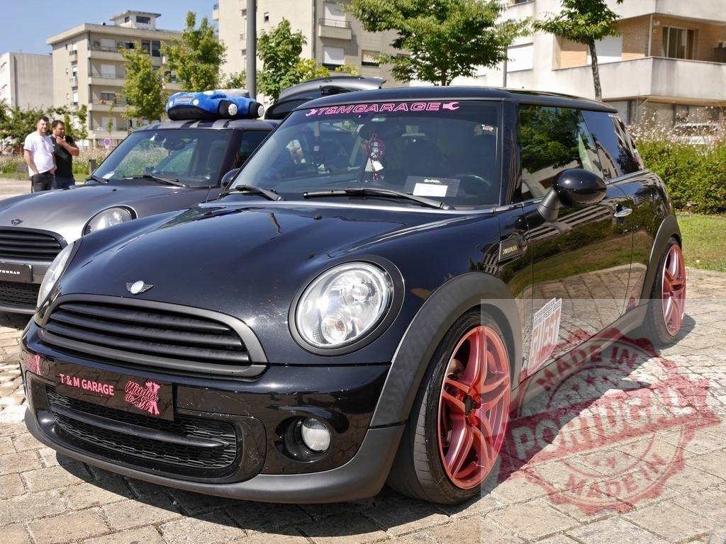 MINI Cooper hatchback with custom pink rims at car show | Custom tuned black MINI Cooper hatchback parking on cobblestone showing unique style - Realized with Pictrs.com