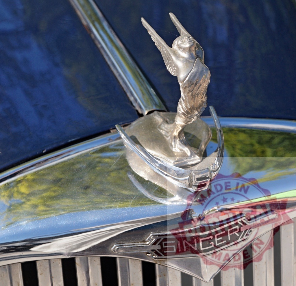 Singer classic car hood ornament winged woman | Singer vintage automobile featuring a chrome winged woman hood ornament and emblem - Realized with Pictrs.com