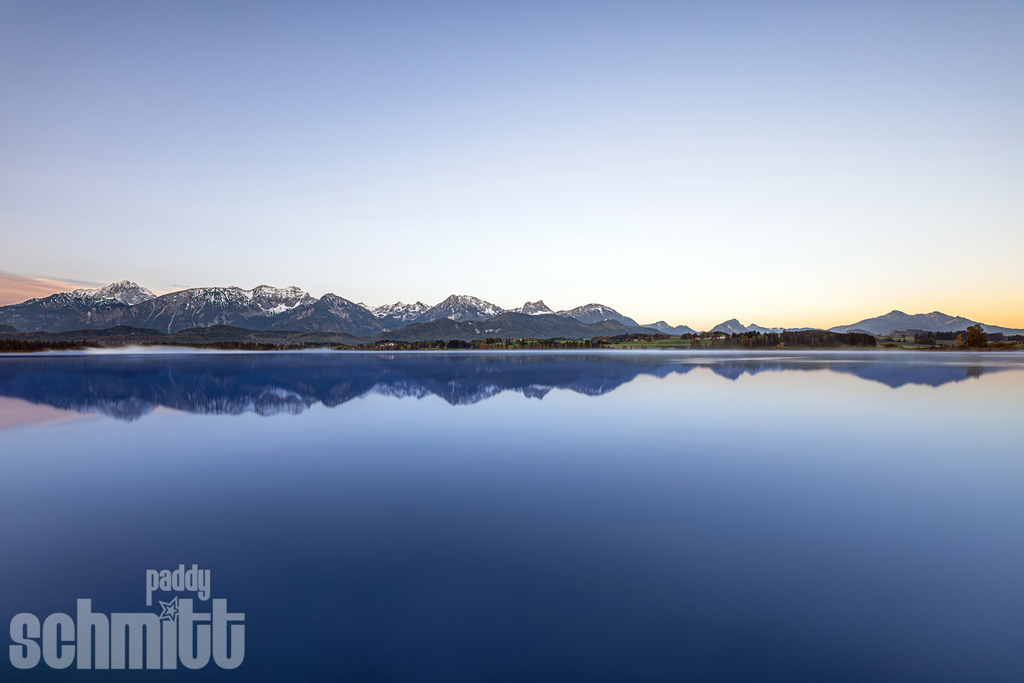 Wasserspiegelung der Alpen am Forggensee bei Füssen im Allgäu | Idyllische Wasserspiegelung der Alpen am Forggensee bei Füssen im Ostallgäu. Das ruhige Wasser und die markante Bergkulisse schaffen eine harmonische und stimmungsvolle Landschaftsaufnahme. - Realisiert mit Pictrs.com