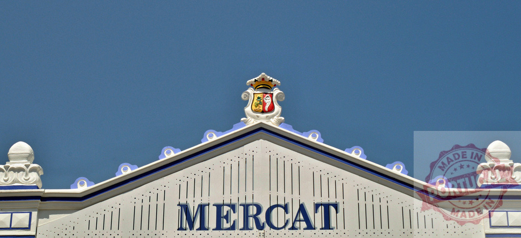 Mercat del Cabanyal facade with shield against blue sky | Mercat del Cabanyal building facade featuring its shield ornament and market name - Realized with Pictrs.com