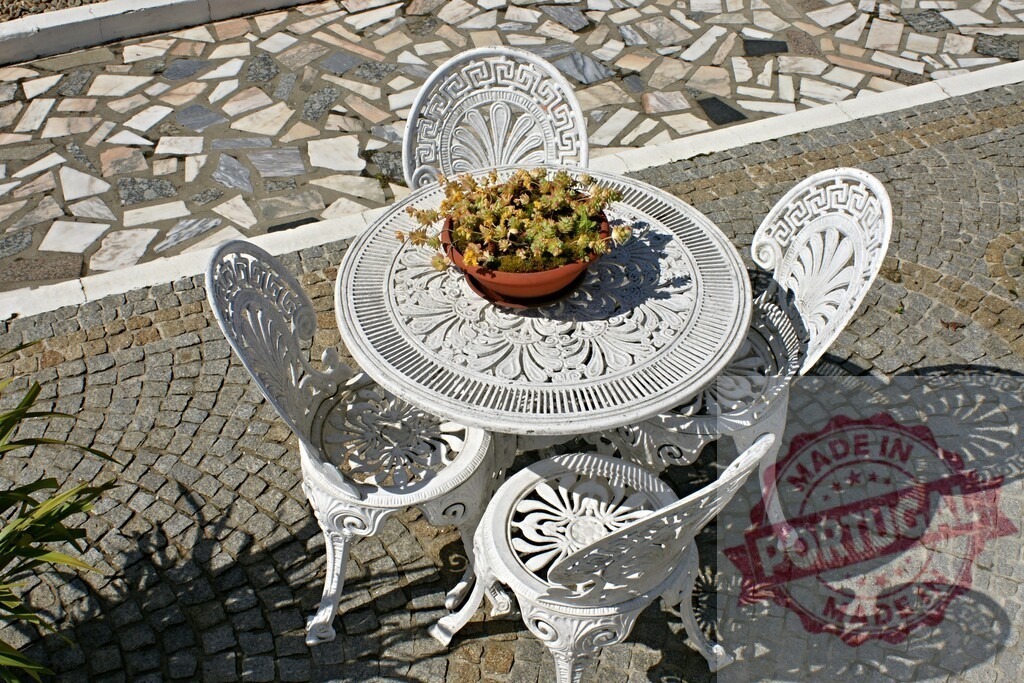 White wrought iron patio furniture set with plant | White cast iron garden furniture sits on a stone paved patio enjoying sunlight - Realized with Pictrs.com