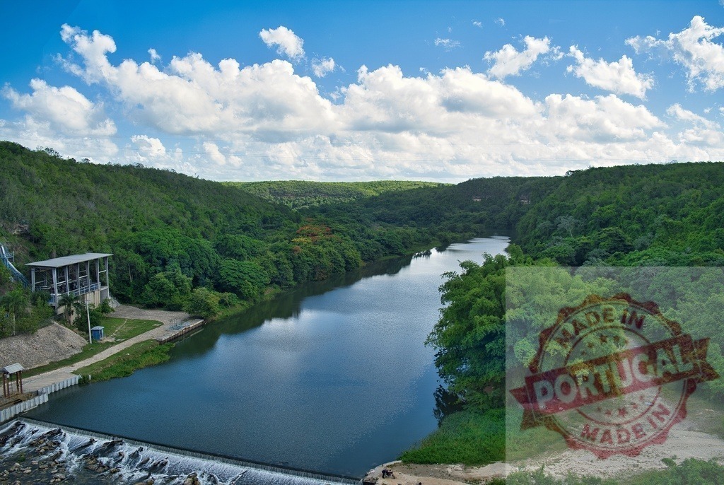 Chavon river winding through green tropical landscape in Dominican Republic | Chavon river flowing through lush green hills under a bright blue sky with white clouds - Realisiert mit Pictrs.com
