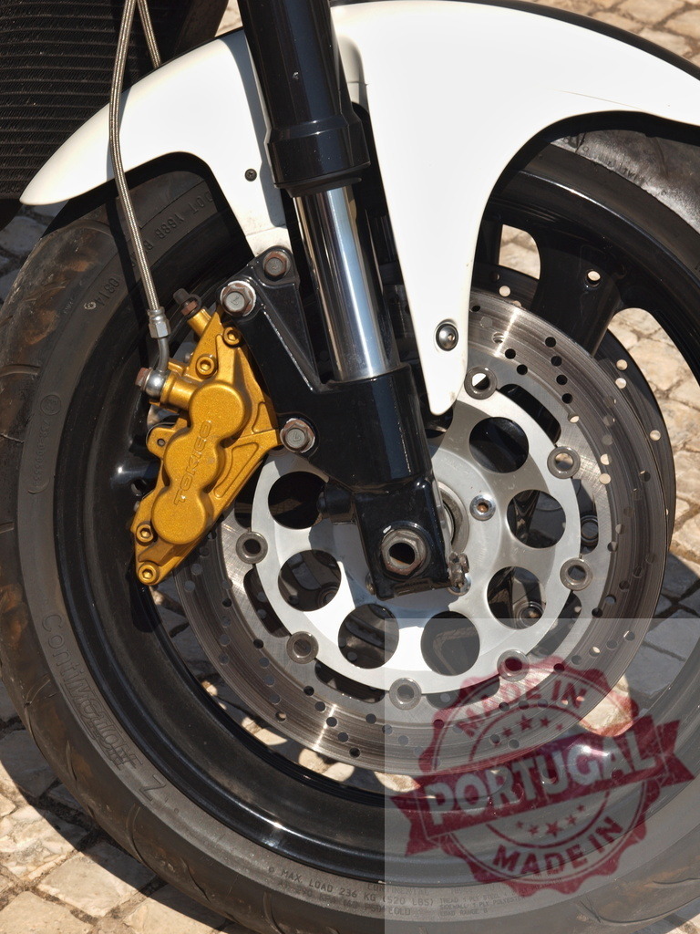 Motorcycle front wheel featuring a gold brake caliper | Motorcycle front wheel with disc brake system and golden caliper for stopping performance - Realisiert mit Pictrs.com