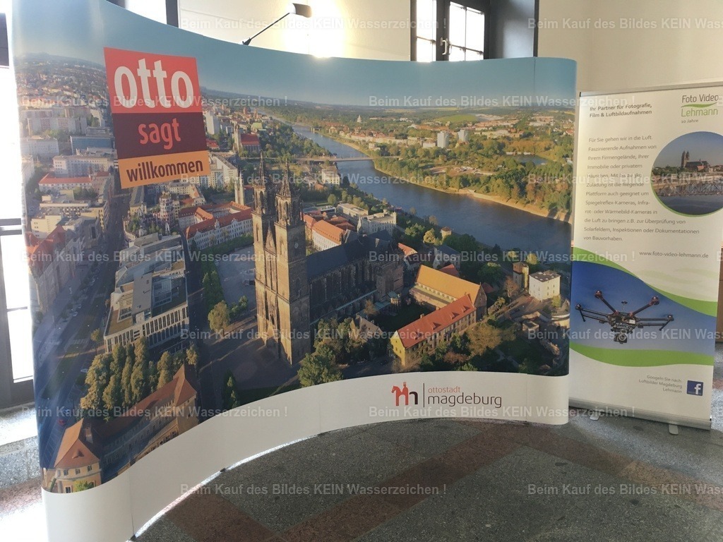 IMG_4087 | Ein Luftbild heißt Gäste willkommen--- Es gibt Fotos, die begleiten einen viele Jahre. Und dann gibt es Bilder, die plötzlich zu Botschaftern einer ganzen Stadt werden. Mit dem Slogan „Magdeburg sagt willkommen“ wurde eines meiner Luftbilder für die Begrüßung von Gästen und Besuchern eingesetzt. Als ich den rund drei Meter hohen Aufstelleri m Magdebutger Rathaus sah, war das für mich ein ganz besonderer Augenblick. Mein Luftbild war nicht mehr nur eine Fotografie. Es war das erste, was viele Menschen von Magdeburg sahen. Dieser Gedanke hat mich sehr berührt. Als Fotograf gibt es kaum ein schöneres Kompliment, als wenn die eigene Heimat genau dieses Bild auswählt, um Besucher willkommen zu heißen.--- In solchen Momenten wird einem bewusst, dass Fotografie mehr ist. Sie kann Identität schaffen, Emotionen wecken und eine Stadt repräsentieren.  Es ist ein schönes Gefühl zu wissen, dass eines meiner Luftbilder dazu beitragen durfte, Magdeburg von seiner schönsten Seite zu zeigen. - Realisiert mit Pictrs.com