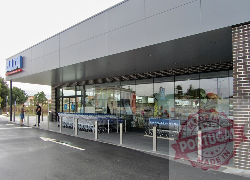 ALDI supermarket facade with shopping carts and entrance | ALDI supermarket building facade with brand logo, glass windows, and a line of shopping carts - Realized with Pictrs.com