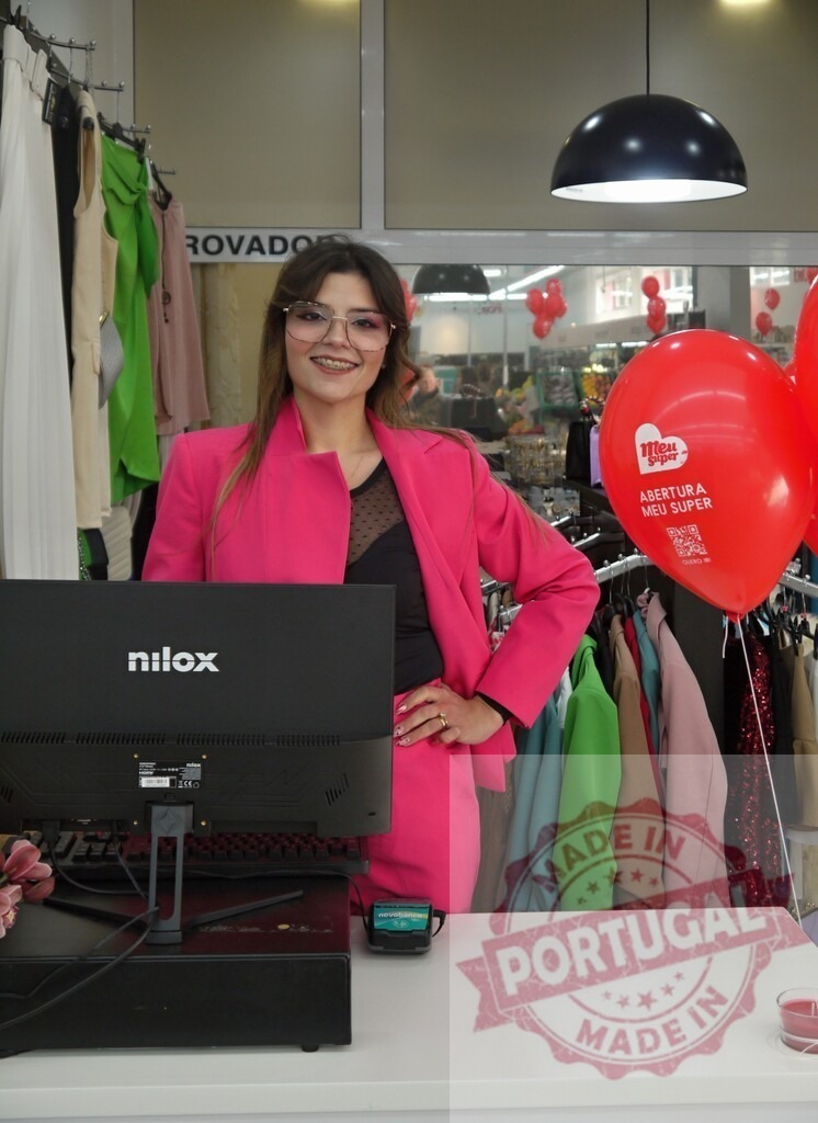 Saleswoman smiling at register in clothing store | Young woman working as a cashier, smiling confidently in a modern retail fashion store - Realisiert mit Pictrs.com