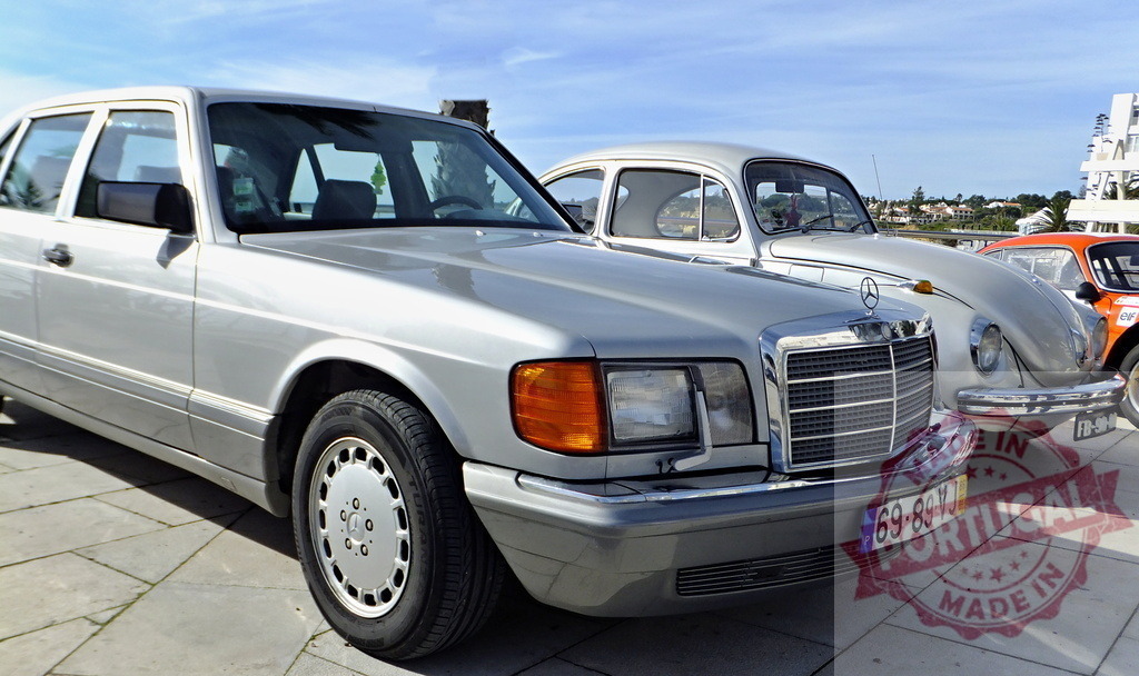 Classic cars parked outdoors showing different models and colors on a sunny day | Silver Mercedes-Benz W126 S-Class parking next to Volkswagen Beetle and racing car - Realisiert mit Pictrs.com
