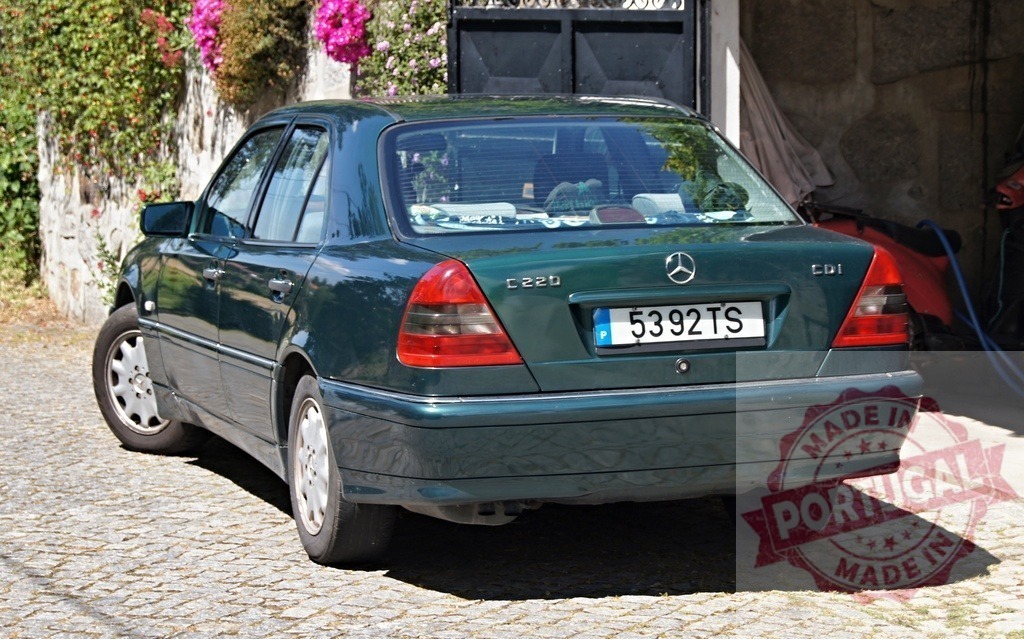 Mercedes-Benz C220 CDI sedan parked on a cobblestone driveway | Dark green Mercedes-Benz C220 CDI parked outdoors on a sunny day - Realized with Pictrs.com