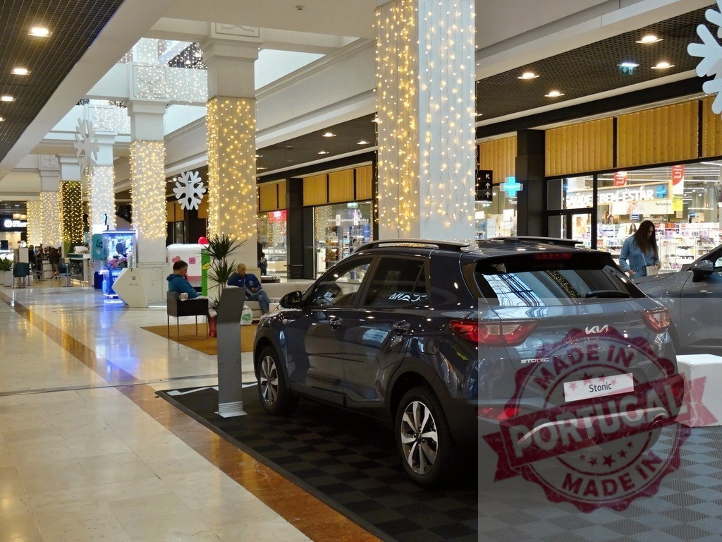 Kia Stonic car display in shopping mall during holiday season | Kia Stonic car showcased in a modern shopping mall interior decorated with festive holiday lights - Realisiert mit Pictrs.com