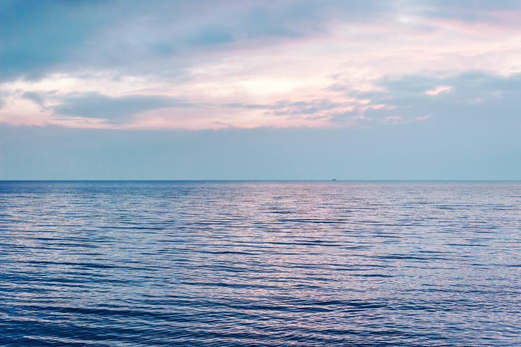 Edel-minimalistische Meeresfotografie – Sanfte Morgenstimmung über ruhigem Wasser | Dezente maritime Wandkunst | Die ersten Lichtstrahlen des Tages tauchen den weiten Horizont in ein sanftes Spiel aus kühlem Blau und zarten Pastelltönen. Die ruhige Oberfläche des Wassers spiegelt die friedliche Stimmung eines frühen Morgens an der Küste wider und schenkt dem Raum eine Atmosphäre von Klarheit und neuer Energie. Ein minimalistisches Werk, das durch seine stille Weite besticht und eine edle, konzentrierte Ruhe in den Wohnbereich bringt.