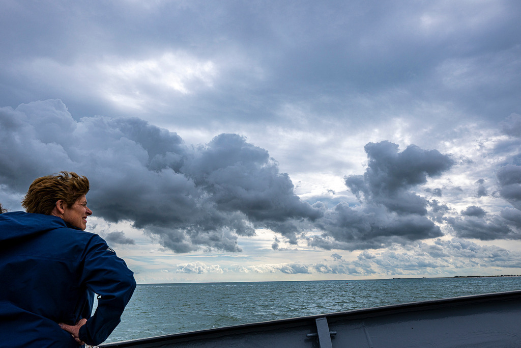 Dramatische Wetterfront über der Nordsee: Schauerzelle nähert sich Texel | Eine dunkle, bedrohliche Regen- und Schauerzelle zieht über die Nordsee vor der Insel Texel auf. An Deck eines Schiffes beobachtet eine Frau in wetterfester Kleidung die faszinierende meteorologische Szenerie. Das kontrastreiche Wetterfoto fängt den typischen maritimen Wetterwechsel an der Küste ein und eignet sich perfekt für redaktionelle Beiträge zu Themen wie Meteorologie, Küstenwetter, Unwetterwarnungen, Klimawandel und Urlaubswetter. - Realisiert mit Pictrs.com