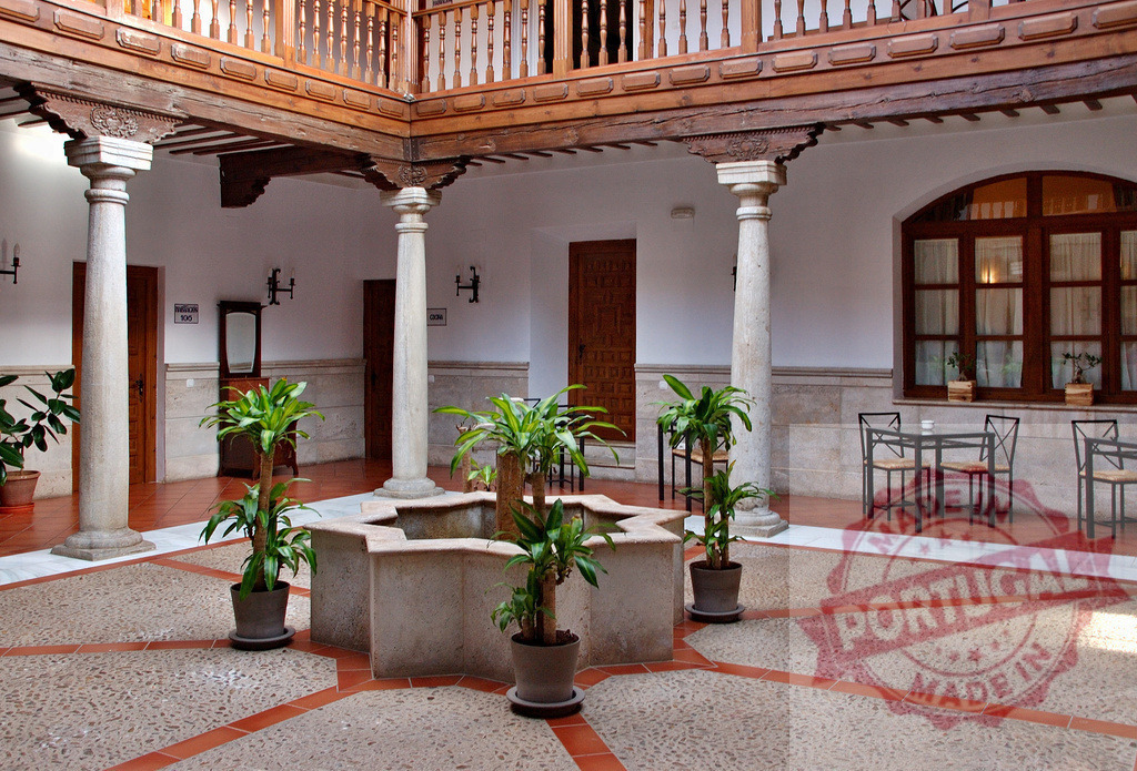 Traditional Spanish courtyard with fountain and wooden balcony. Extremdura - Spain | Spanish patio featuring a fountain, columns, and a traditional timber balcony for relaxation - Realisiert mit Pictrs.com