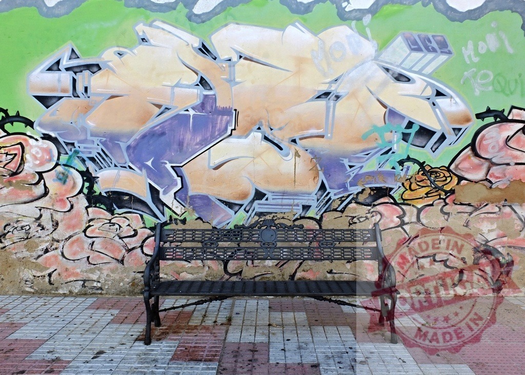 Empty park bench in front of colorful urban graffiti wall | Empty black metal bench standing against a vibrant wall with street art and abstract shapes - Realized with Pictrs.com