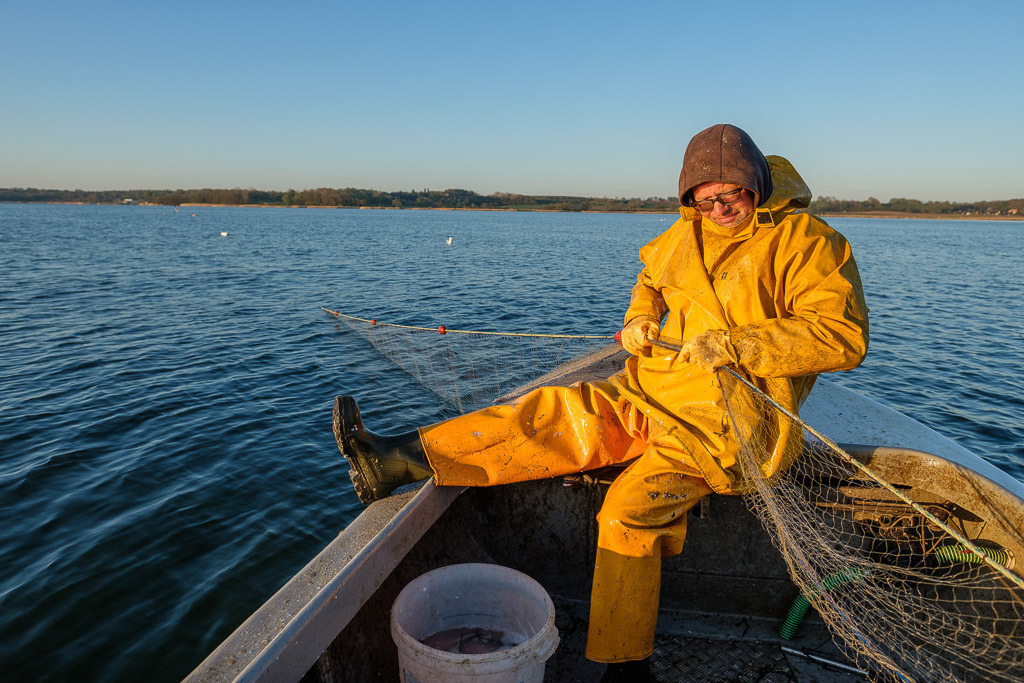 zeitenwende-farbe-03-18 | Matthias Nanz aus Schleswig ist einer der letzten Berufsfischer an der Schlei. Mit seinem Boot fährt er vom Liegeplatz in Missunde zu den Fanggründen in der Schlei. An diesem Fangtag Ende April 2020 gingen vor allem Heringe ins Netz. Das Einholen erfolgt ohne Motorhilfe und ist eine große Kraftanstrengung. - Realisiert mit Pictrs.com