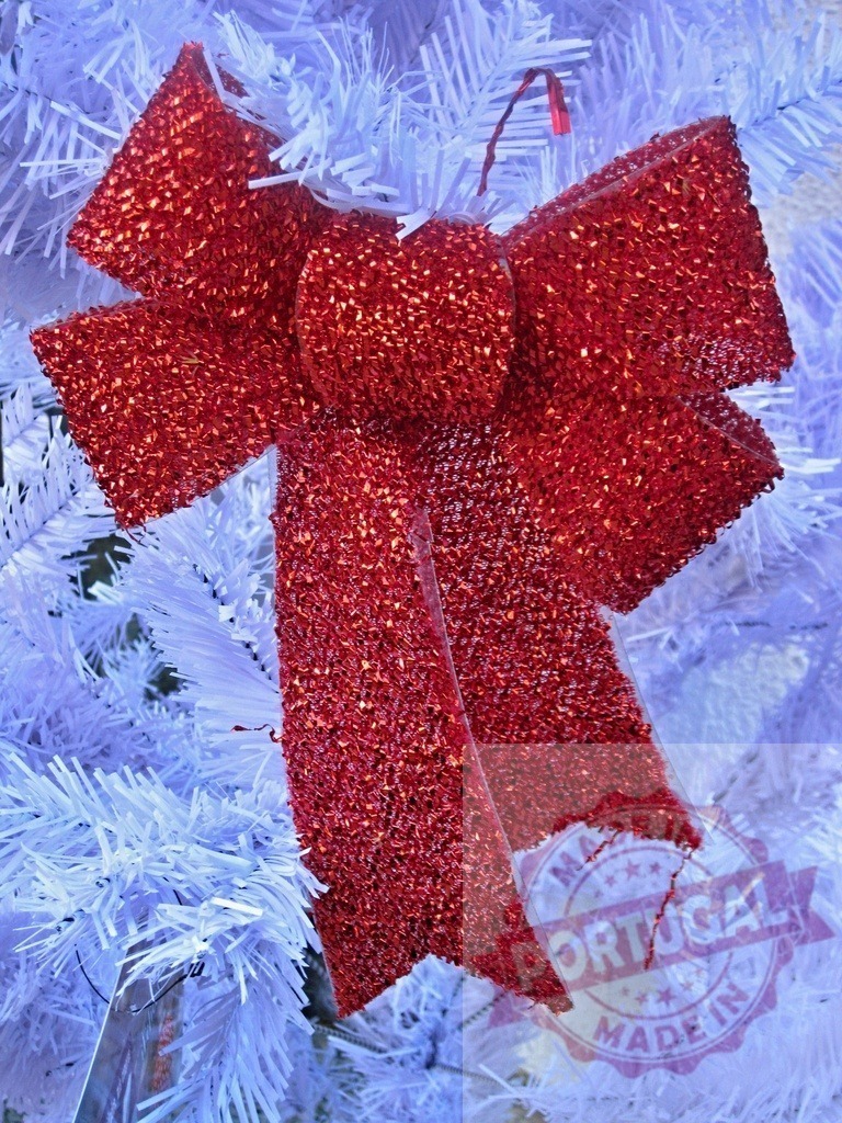 Glittering red christmas bow hanging on white christmas tree | Shiny red christmas bow hanging on a white christmas tree as a festive decoration - Realisiert mit Pictrs.com