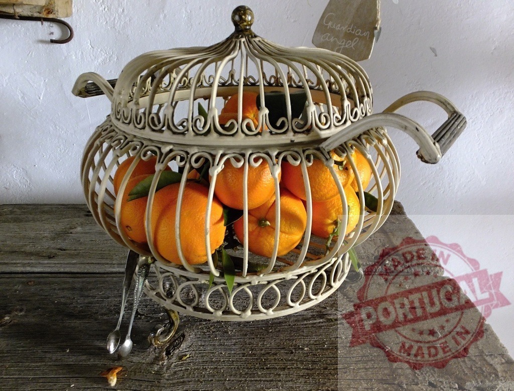 Oranges in decorative wire basket on rustic wood | Fresh oranges filling an ornate metal fruit basket on a worn wooden table - Realisiert mit Pictrs.com