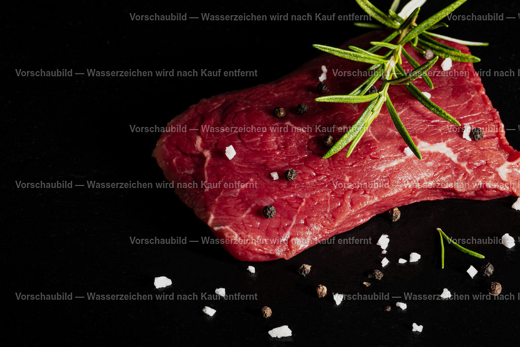 rohes Rinder Hüftsteak auf schwarzer Schieferplatte angerichtet | rohes Rinder Hüftsteak auf schwarzer Schieferplatte angerichtet. Dekoriert mt einen Zweig Rosmarien, Pfefferkörnern und groben Salz - Realisiert mit Pictrs.com